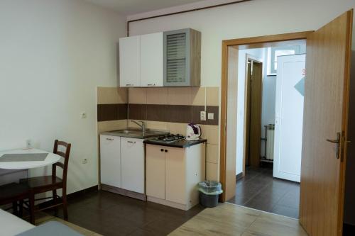 une petite cuisine avec des placards blancs et une table dans l'établissement Apartment Eurho, à Osijek