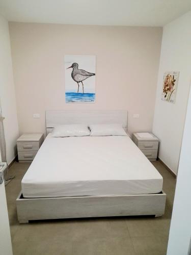 a bedroom with a bed with a bird painting on the wall at La Casera in Lido di Dante