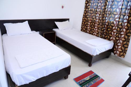 a bedroom with two beds and a rug at Dwarka Home Stay in Bodh Gaya