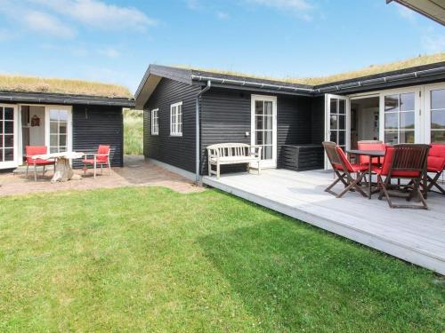 a deck with red chairs and a table on a house at Holiday Home Ovelil - 650m from the sea in Western Jutland by Interhome in Vejers Strand