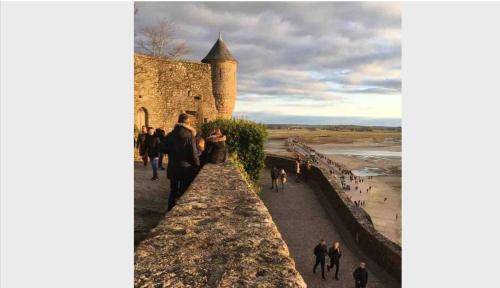 a group of people walking on the wall of a castle at Maison familiale à 10 min du Mont Saint Michel in Pontorson