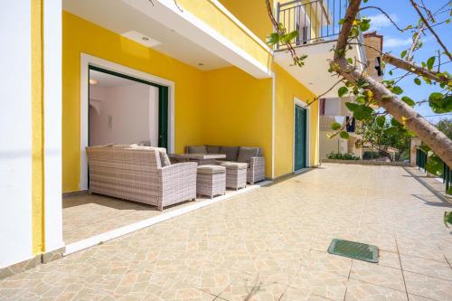 an outdoor patio with couches and a yellow wall at Niko's Central Skala Apartments in Skala Kefalonias