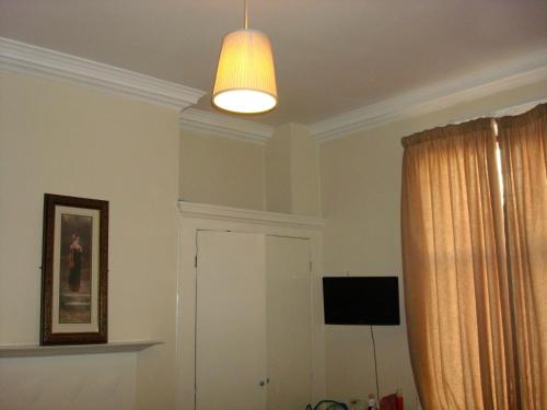 a living room with a light hanging from a ceiling at Forest Gate Hotel - Free Parking limited spaces in London
