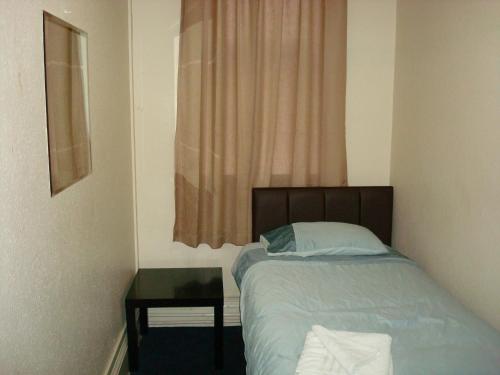 a bedroom with a bed and a table and a window at Forest Gate Hotel - Free Parking limited spaces in London