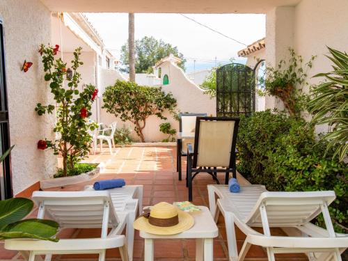 un patio con sillas blancas y mesas con sombrero en Apartment Alba by Interhome, en Nerja
