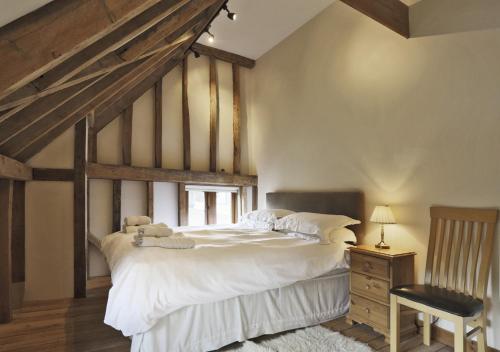 a bedroom with a large white bed and a chair at Red House Barns Sternfield in Friston