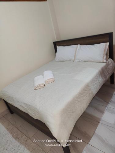 a bedroom with a bed with two towels on it at Tranquil Homes in Nanyuki