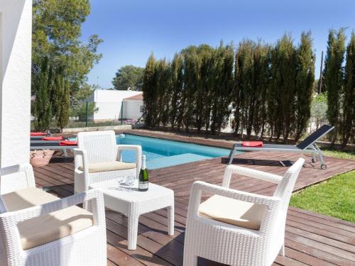 un patio con sillas blancas, una mesa y una piscina en Villa Villa Luxor by Interhome, en L'Ametlla de Mar