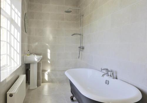 a white bathroom with a tub and a sink at Park Farm House in Wangford