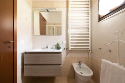 een badkamer met een wastafel, een toilet en een spiegel bij Sweet Home Contignano in Contignano