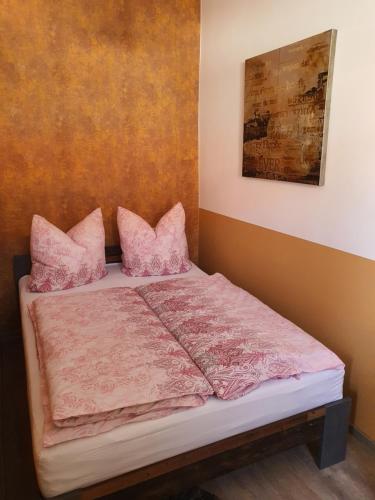 a bed with pink sheets and pillows in a room at modern und mittendrin, das ist Monty in Wittenberge