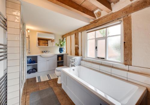a bathroom with a tub and a toilet and a window at Perry Acres Cottage in Saxtead