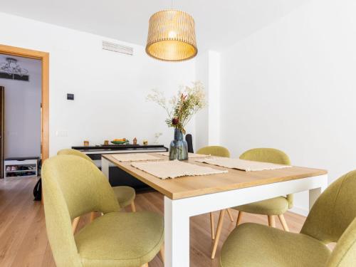 a dining room with a wooden table and green chairs at Holiday Home Casa de Palmera dels Munts by Interhome in Torredembarra