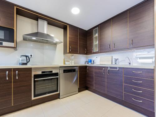 a kitchen with wooden cabinets and stainless steel appliances at Holiday Home Casa de Palmera dels Munts by Interhome in Torredembarra