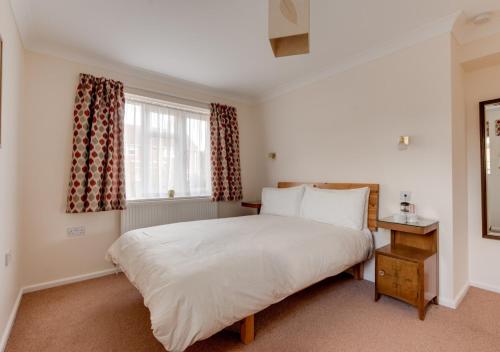 - une chambre avec un grand lit blanc et une fenêtre dans l'établissement Poppy Corner, à Southwold