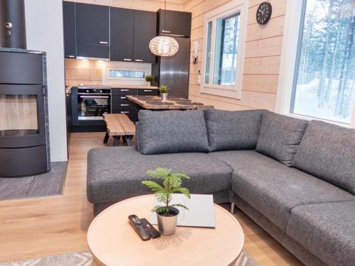 ein Wohnzimmer mit einer grauen Couch und einer Küche in der Unterkunft Holiday Home Mäkitie 2 by Interhome in Aikkila