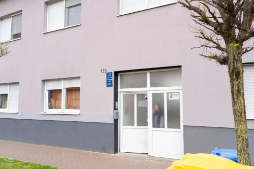 a building with a white door and a tree at Apartment Eurho in Osijek