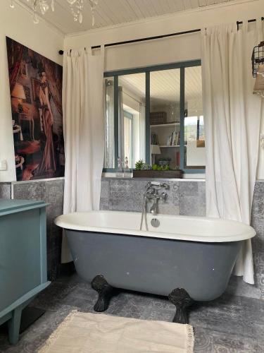 La salle de bains est pourvue d'une baignoire et d'un miroir. dans l'établissement Maison sur cour, à Courzieu