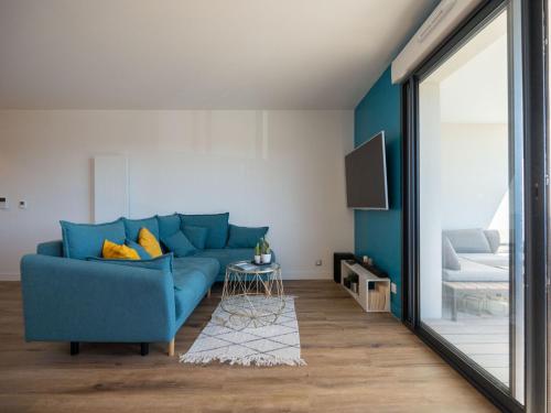 ein blaues Sofa im Wohnzimmer mit Spiegel in der Unterkunft Apartment Le Rooftop by Interhome in Lacanau-Océan