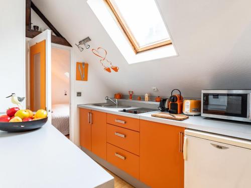 una cocina con armarios naranjas y un bol de fruta en la barra en Apartment Les Voiles by Interhome, en Trouville-sur-Mer