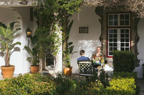 a man and woman sitting at a table in front of a house at Pergola Boutique Hotel in Cascais