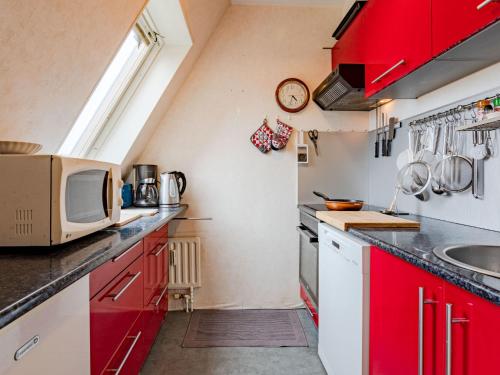 une cuisine avec des armoires rouges et un micro-ondes dans l'établissement Apartment Bel Cabourg-7 by Interhome, à Cabourg