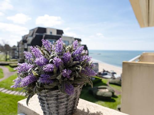a vase of purple flowers sitting on a wall near the beach at Apartment Le Domaine des roches by Interhome in Trouville-sur-Mer