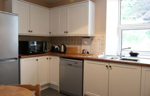 a kitchen with white cabinets and a sink at School House in Dunan