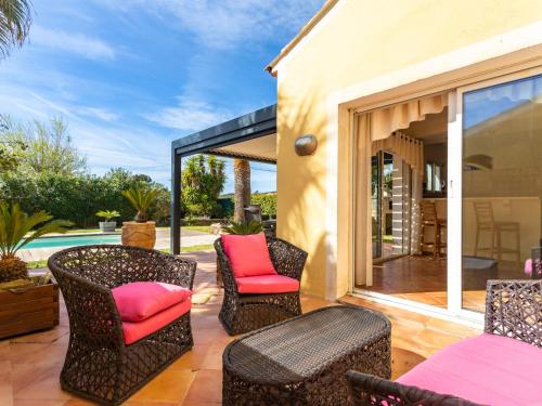 patio z wiklinowymi krzesłami i różowymi poduszkami w obiekcie Holiday Home Maison Boutons d'Or by Interhome w mieście Bormes-les-Mimosas