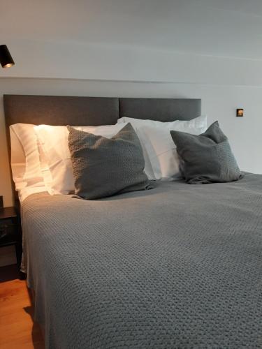 1 cama con almohadas blancas y edredón gris en Loft Style Studio Apartment- Free Parking- Free Gym- Keyless Access en Tartu