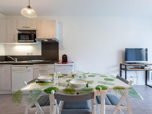 a kitchen with a dining table with chairs and a kitchen with at Apartment Cap Aréa by Interhome in Labenne