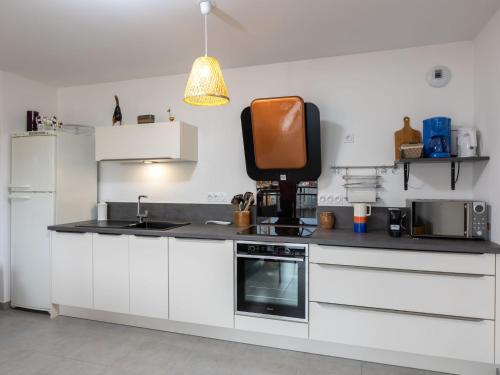 une cuisine avec des armoires blanches, un évier et un micro-ondes dans l'établissement Apartment Résidence Newquay-1 by Interhome, à Dinard
