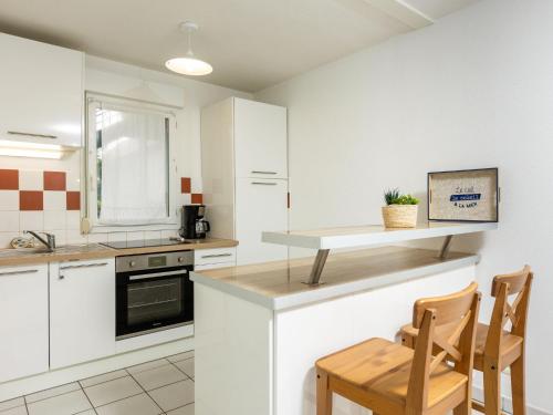 kuchnia z białymi szafkami, stołem i krzesłami w obiekcie Apartment Les Caps Horniers by Interhome w mieście Pleurtuit
