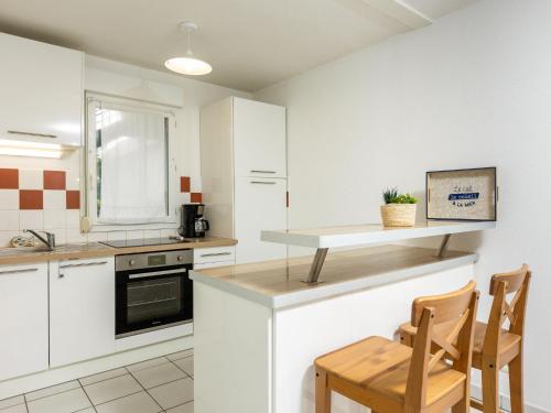 PleurtuitにあるApartment Les Caps Horniers by Interhomeの白いキャビネット、テーブルと椅子付きのキッチンが備わります。