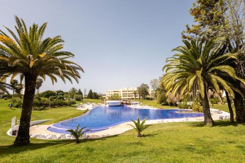 a large swimming pool in a park with palm trees at Marachique Villa - Torralvor in Alvor