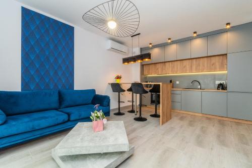 a living room with a blue couch and a kitchen at Flatbook Apartamenty - Sztutowo Baltic Twins in Sztutowo