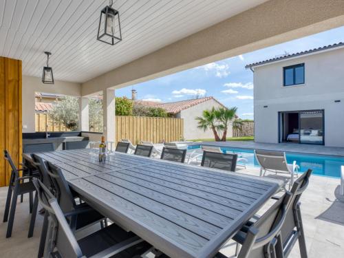 einen Tisch und Stühle auf einer Terrasse mit Pool in der Unterkunft Villa Villa des écureuils by Interhome in Lanton