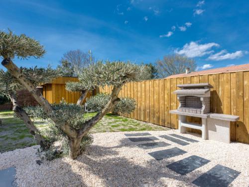 einen Hinterhof mit Grill neben einem Zaun in der Unterkunft Villa Villa des écureuils by Interhome in Lanton