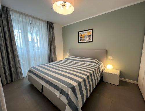 ein Schlafzimmer mit einem gestreiften Bett und einem Fenster in der Unterkunft Ca' Ariston in Grado