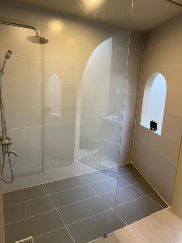 a bathroom with a shower with a glass door at escVACA - Your Stay in Mui Ne in Mui Ne