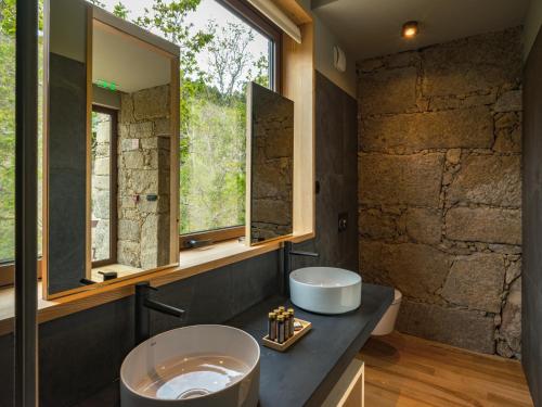 a bathroom with two sinks and a stone wall at Lavandeira Douro Nature & Wellness in Ancede
