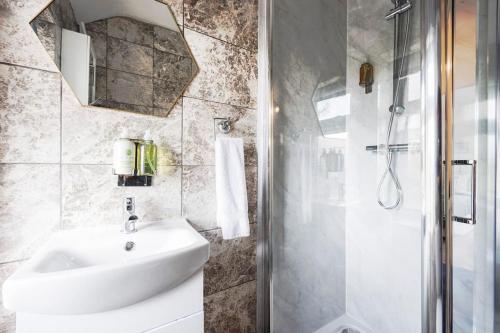 W łazience znajduje się biała umywalka i prysznic. w obiekcie Stunning 2 Bed House with Parking in Dagenham w mieście Goodmayes