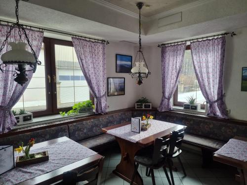 a dining room with purple curtains and tables and windows at Pension Heuhexe in Fladungen