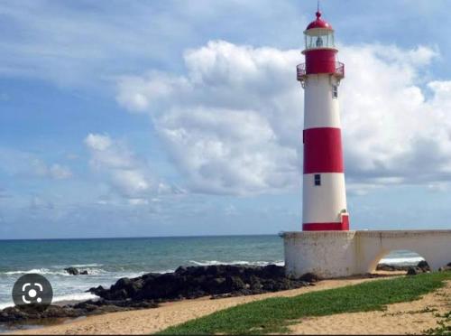 a red and white lighthouse sitting on the beach at AP Itapuã in Salvador
