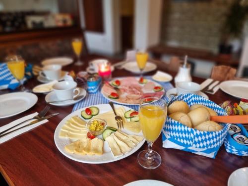 a wooden table with plates of food and glasses of orange juice at Pension Heuhexe in Fladungen