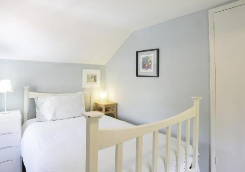 a bedroom with a white bed and a crib at Sherfield Cottage in Snape