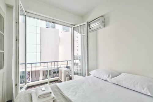 une chambre avec un lit blanc et une grande fenêtre dans l'établissement L29 Lenval beach at 1min walk to Sea front AC Balcony, à Nice