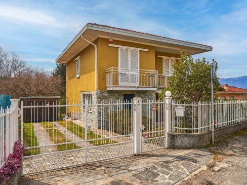 ein gelbes Haus mit einem weißen Zaun in der Unterkunft Apartment Mottarone by Interhome in Laveno-Mombello