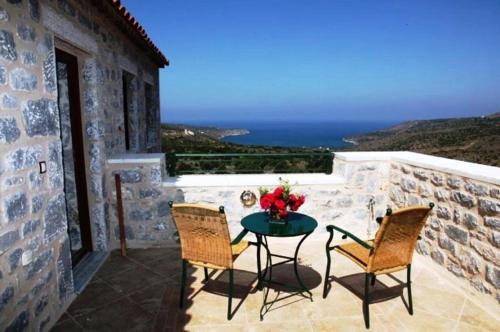 a patio with a table and two chairs and the ocean at Althea Village in Areopolis