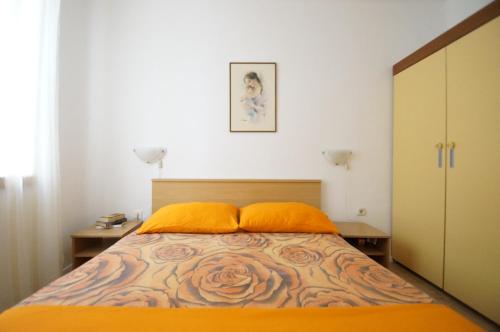 1 dormitorio con 1 cama con almohadas de color naranja en Apartments Ani, en Vela Luka